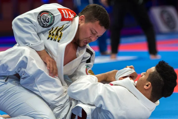 ABU DHABI, UAE - 19 Nisan 2016: ABU DHABI World PROFESSIAL JIU-JITSU CHAMPIONSIP 2016, IPIC ARENA. Beyaz kimonolu dövüşçüler paspasın üzerinde dövüşüyor..
