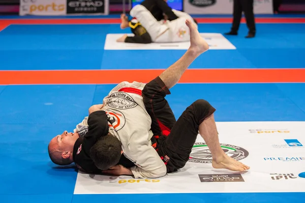ABU DHABI, UAE - 19 Nisan 2016: ABU DHABI World PROFESSIAL JIU-JITSU CHAMPIONSIP 2016, IPIC ARENA. Mavi hasırda dövüşçüler.
