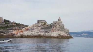 Liguria, İtalya 'da ünlü tarihi kilise Chiesa di San Pietro ve Porto Venere' deki Doria Kalesi 'nden geçiyor. Küçük bir tekne bir kayanın yanından geçiyor..