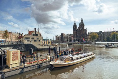 Amsterdam - 02 Ekim 2022 Saint Nicholas Bazilikası 'nın karşısındaki merkez istasyon yakınındaki teknede turistler.