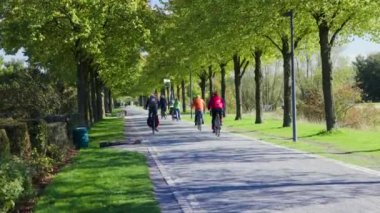 Bisikletçiler, Almanya 'nın Essen kenti yakınlarındaki Nordsternpark' ta güneşli havada yol boyunca at sürüyorlar..