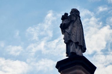 Famous statue from behind on Charles Bridge in Prague against the sky.