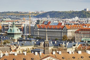 Tower construction crane on the background of the Prague city. Traditional tile roofs and architecture and modern buildings.