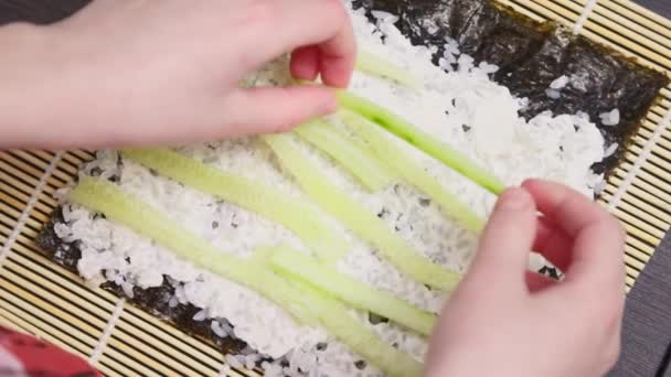Chłopak Robi Sushi Kładzie Posiekane Ogórki Ryżu — Wideo stockowe