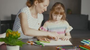 Mom teaches her daughter to draw. She erases the drawing and explains how to draw with a pencil.