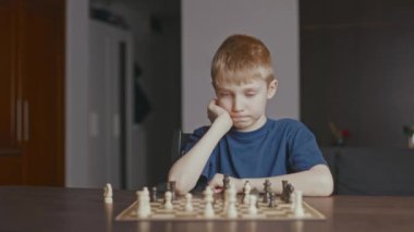 The boy beats figure in chess and looks at you.