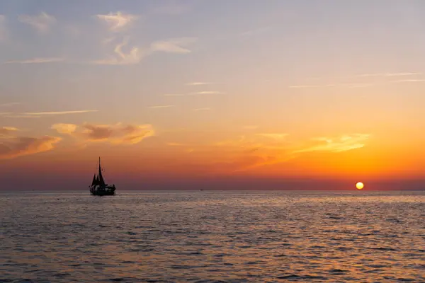 Gün batımında gökyüzünün altında yelkenli bir tekne..