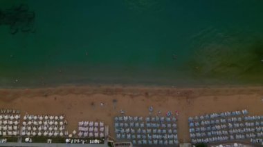 Güneş şemsiyeleriyle gün batımında sahil, hava kararıyor, Avsallar, Türkiye.