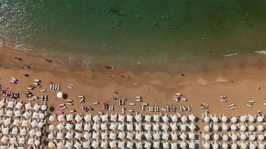 Beyaz şemsiyeli sahil sörfü ve banyo yapan insanlar, güzel gök mavisi suyu, Avsallar, Türkiye.