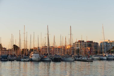 Batan güneş ışınlarının altında şehrin arka planına karşı direkler.