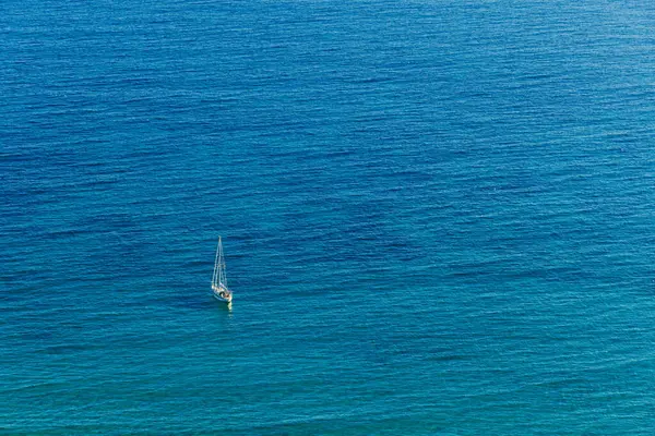 A solitary yacht without sails stands in the sea. Aerial view.