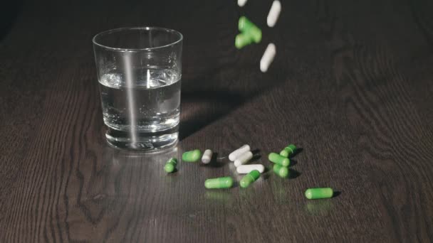 Medische Capsules Gieten Tegen Achtergrond Van Een Glas Water — Stockvideo