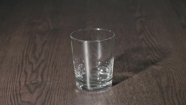 白いカプセルがガラスに注ぎ込まれ 一つはテーブルに落ちている 高品質のスローモーション4K映像 — ストック動画