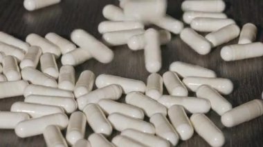 Koyu bir masaya düşen beyaz kapsüller..