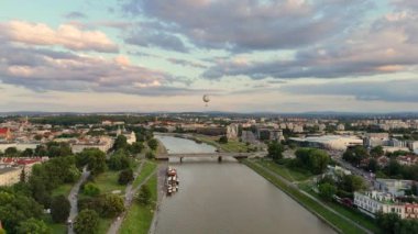 Gün batımında Krakow 'daki Vistula Nehri' nde. Sıcak hava balonu uzaktan görülebilir, dramatik bulutlarla. Hava görüntüsü.