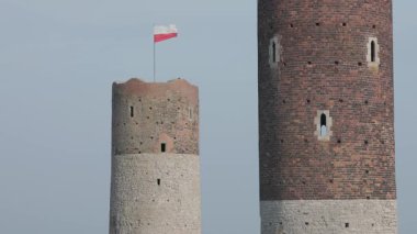 Polonya bayrağı gururla Polonya 'daki Checiny Castle' ın tarihi kulesinin tepesinde dalgalanır, temiz gökyüzüne karşı ulusal mirası ve gururu simgeler..