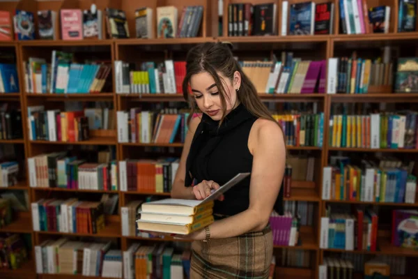 在大学图书馆找一本书的年轻女学生 — 图库照片