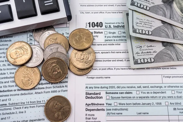 Many important tax form blanks with dollar bills and a pen on a calendar page marking an important date . tax forms