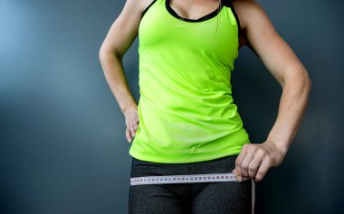 Yakın plan, eğitimli bir mideyi mezurayla ölçüyor. Spor, spor ve diyet konsepti. Vücut boyutlarının ölçümü