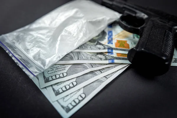 Cocaine in bags next to dollars and a gun isolated on a black background. the concept of breaking the law. storage and distribution of cocaine