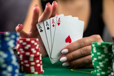 Genç bir kadın masada oturmuş poker oynuyor ve elinde gururla zaferi ve başarıyı kutluyor. Çok heyecanlı. Poker oynayan kadın.