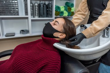 Genç ve güzel bir müşteri özel bir maskeyle berbere geldi ve usta salgın sırasında saçlarını yıkamak için hazırladı. Kuaför konsepti