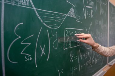 Tebeşirle kadın eli ve tahtaya matematik formülü yazmak. Eğitim konsepti. sınıf