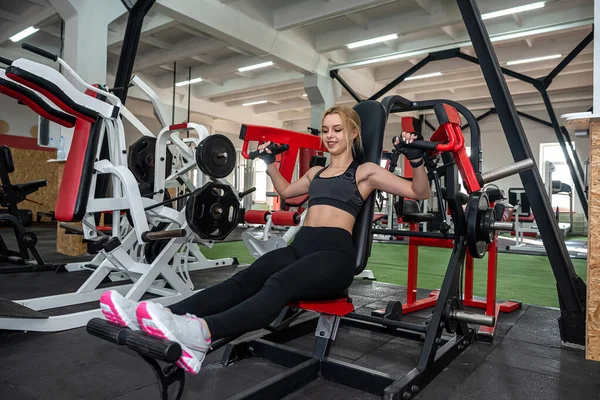 beautiful young girl with a sports figure is engaged in the gym for health. The concept of a healthy lifestyle