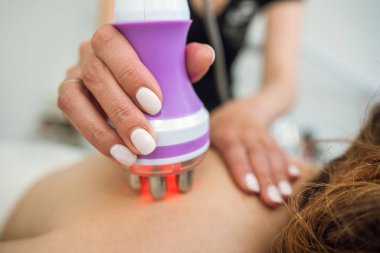 masseur use hardware anti-cellulite massage her female client as anticellulite procedure for loss weight