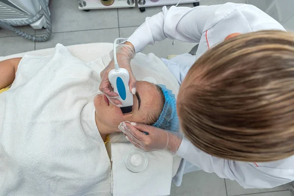 stock image woman lies in the beautician's office during a facial moisturizing procedure. A cosmetologist applies a moisturizing mask to the patient's face. beauty salon. cosmetology dermatology