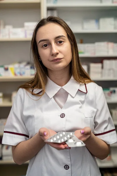 Young smiling female pharmacist marking an assortment of drugs in a pharmacy. Portrait of a pharmacist girl
