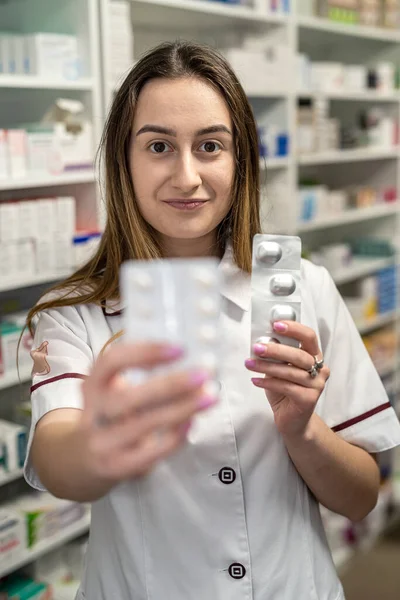 A young female pharmacist reads medicine instructions while standing in the chemist\'s aisle. Pharmacy. Pharmacist. Medicine. Tablets