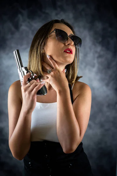 若い美しいセクシーなブルネットの女性は 彼女の手の中に銃を持ってポーズをとっています 銃を持った女だ 武器銃を手に — ストック写真