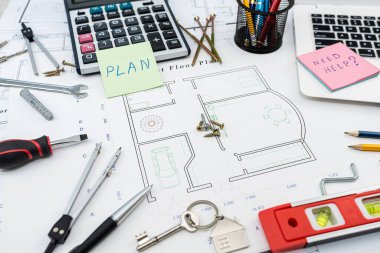 Bina planındaki yeni evlerin planlarının üzerine inşaat araçları saçılmış. Ev onarım servisi konsepti için bir model. Üst görüş nesneleri. İnşaat çalışmaları