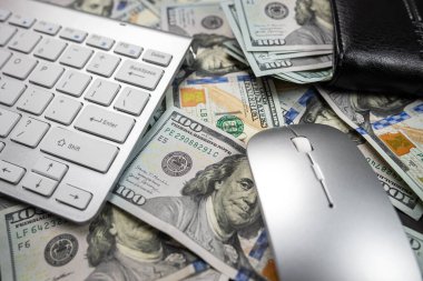 Beyaz bir dizüstü bilgisayarda yığınla Amerikan doları. Yukarıdan bak. Ücretli ofis işi