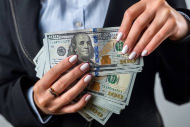 Genç kız elinde büyük bir miktar para tutuyor ve kara bir çantada para sayıyor. Para ve cüzdan. Kadın sağlandı. bolluk