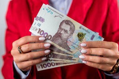 Heyecanlı genç ve neşeli bir kadının pembe arka planda askısız elbiseyle elinde para tutarken fotoğrafı. Kamera işaret ediyor.
