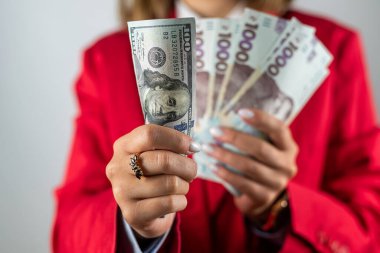 Çok sayıda dolar, yakın çekim ve güzel genç bir kadının ellerinde hryvnialar. İş ve zenginlik kavramı. Eldeki para