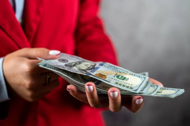 Ceketli bir kadının narin ellerinde bir yığın Amerikan doları var. Dükkandaki bir kadın. Dolarlı eller