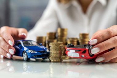 İki araba mankeni tutan bir kadının elleri bozuk para dağı yakınlarında kaza süsü veriyor. Araba sigortası. Araba kazası güvenliği.