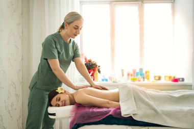 Young prety woman with closed eyes getting relax massage on back, healthy lifestyle