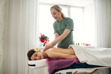 Kadın masajcı, masaj yapan kadının sırtını rahatlatıyor. Terapi ve güzellik tedavisi kavramı.