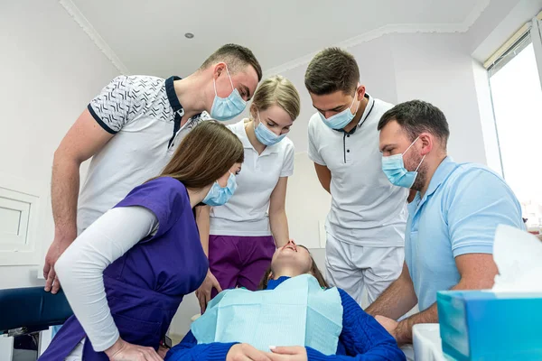 A cheerful group of dentists and their assistants stand in the dental office and smile happily. The concept of working leisure for physicians.