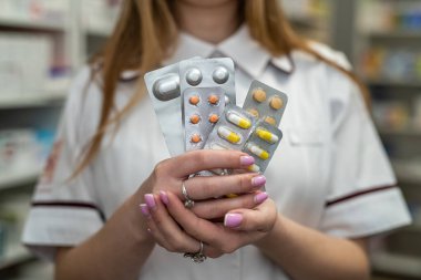 Kadın eczacı elinde karton bir ilaç paketiyle iş yerinde. Sağlık hizmetleri kavramı