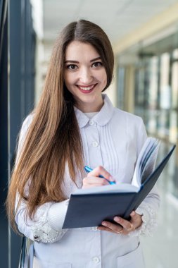 young experienced pediatrician doctor with patient log standing in hospital. Concept of medicine. The pediatrician is a woman. Portrait of a woman