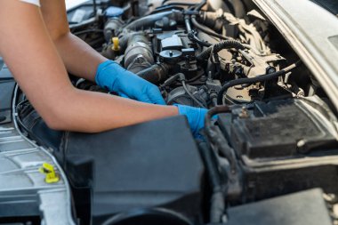 Araba servisinde çalışan profesyonel bir tamircinin yakın plan fotoğrafı. Motor tamir uzmanı. Tamirci eldiven takıyor ve cırcır kullanıyor. Modern temizlik atölyesi.