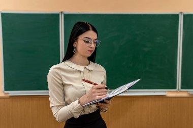 Yeşil karatahta arka planında tebeşirle kadın öğretmenin portresi. Okula geri dön.