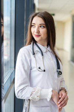 Üniformalı çekici görünümlü bir hemşire koridordaki klinikte hastaları bekliyor. Kadın portresi konsepti. Üniformalı bir doktor.