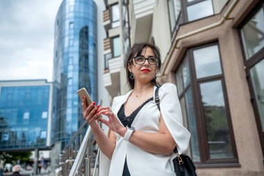 Beautiful business woman using mobile phone to play social media in downtown buildings. Smartphone concept.