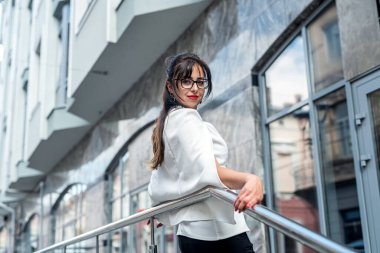 İş elbiseli bir iş kadını büyük bir binanın arka planında dokümanlarla ofise gider. İş merkezine yakın başarılı bir iş kadınının portresi.